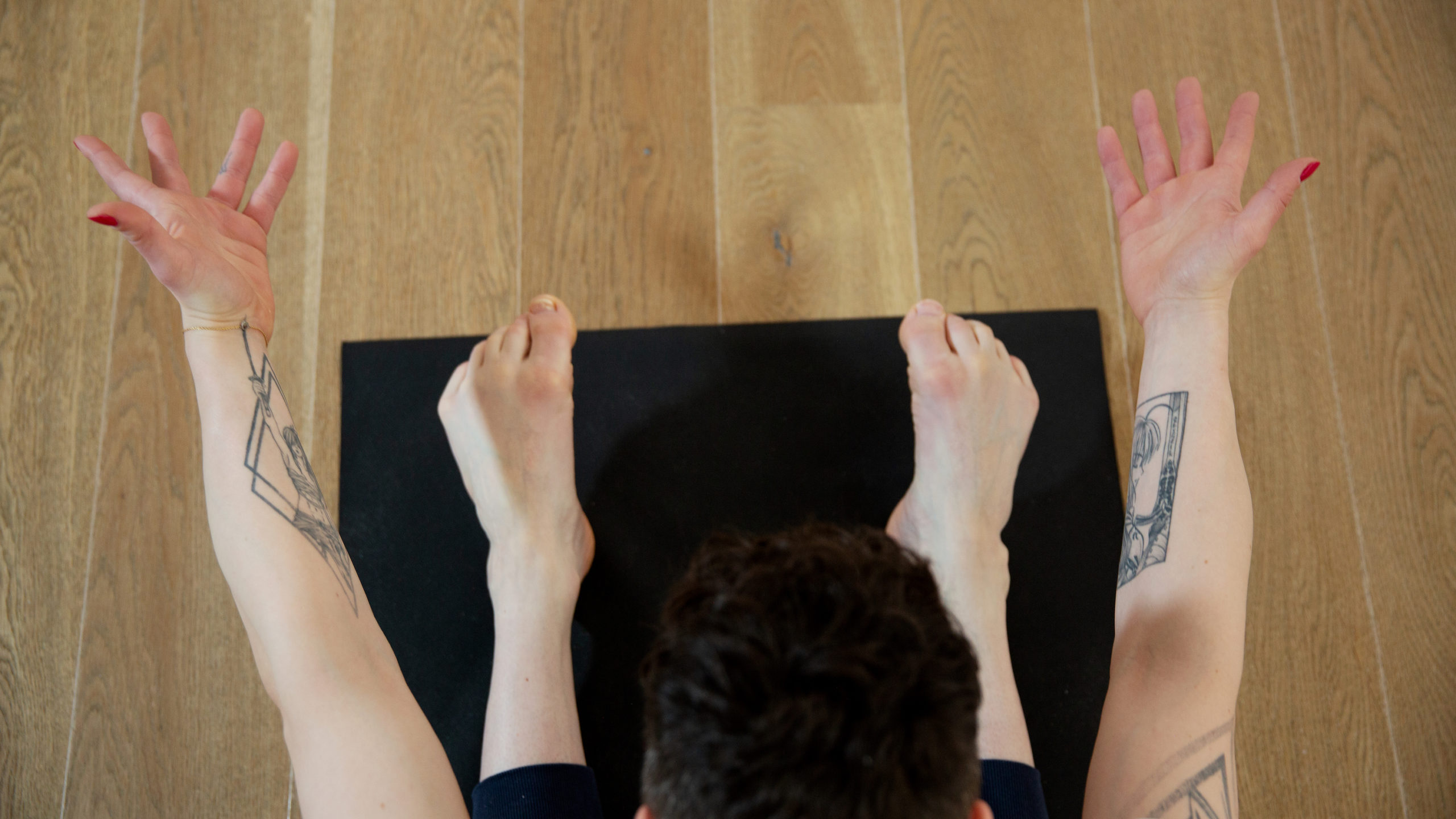 Auf Yogamatte Arme und Beine im Sitzen nach vorne ausgestreckt